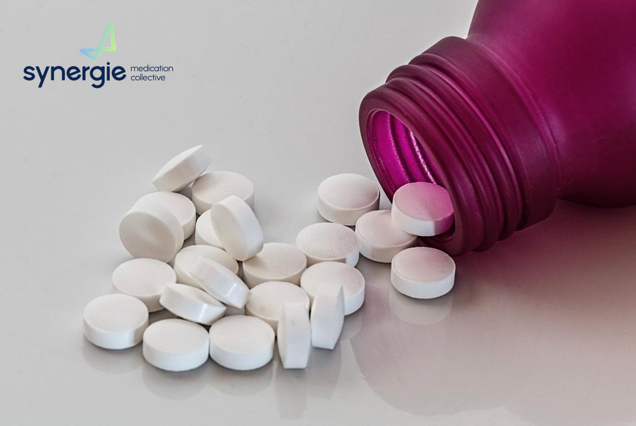 White medication tablets spilling from a bottle, with the Synergie Medication Collective logo