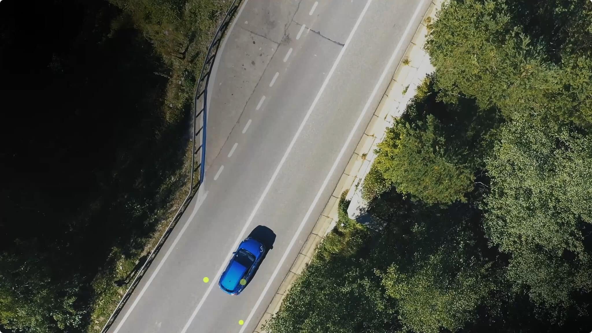 Aerial view of a car on a tree-lined road with GPS waypoint markers, from Point One Navigation's automotive solutions page